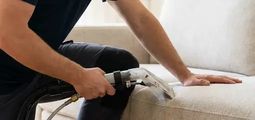 Professional upholstery cleaner deep-cleaning a fabric sofa with a handheld extraction tool, Columbus, OH.